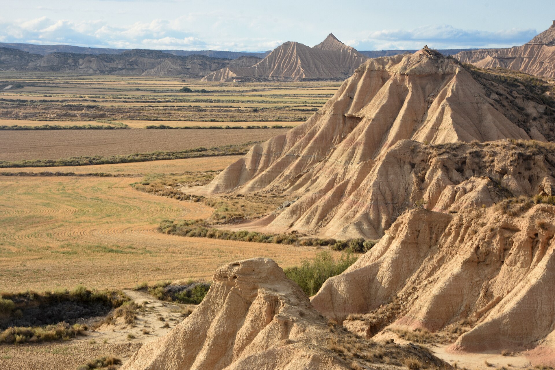 Cabezos de arcilla erosionados por el viento en las Bardenas Reales de Navarra, con campos de cultivo y la llanura de la Ribera al fondo