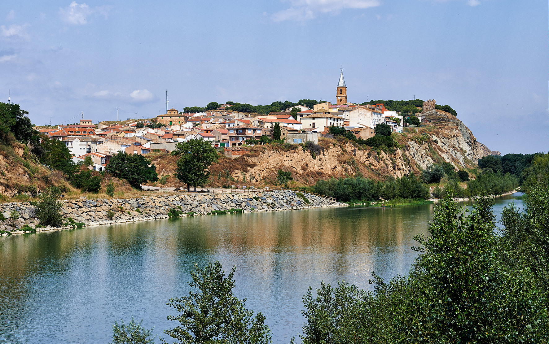 Vista de Milagro, en la Ribera de Navarra, con el caserío y la torre de la iglesia sobre el cortado y el río en primer plano