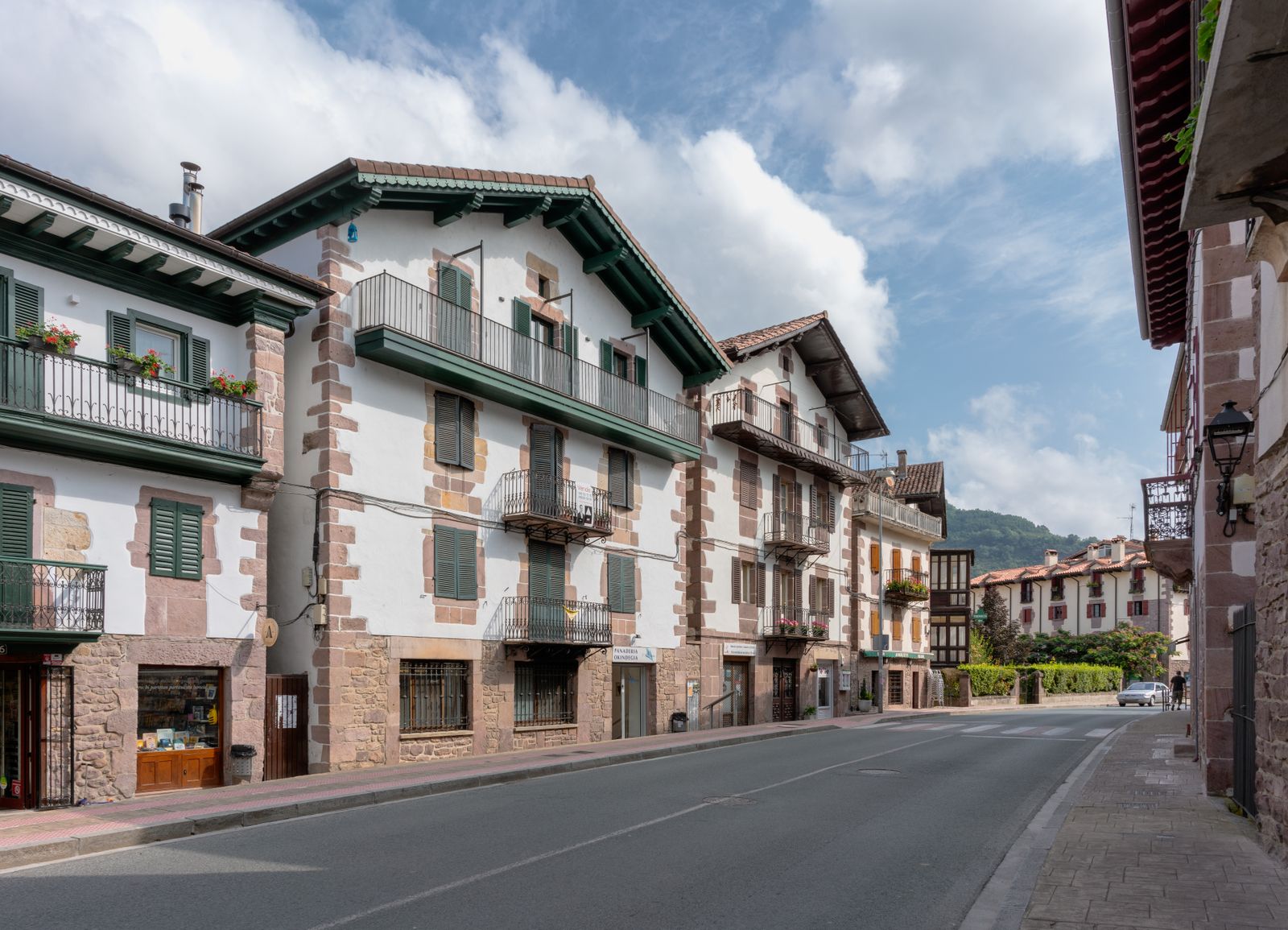 Calle de un pueblo navarro con casas tradicionales de fachada blanca, sillería de piedra y balcones de hierro