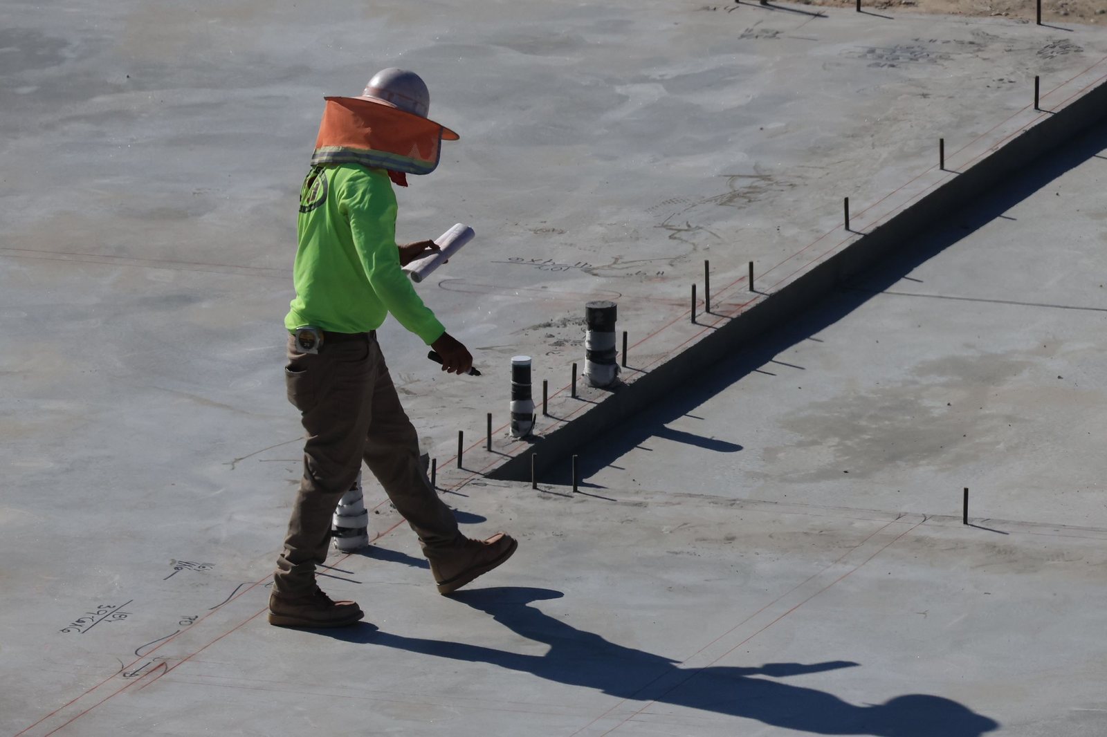 Técnico revisando una solera de hormigón recién ejecutada, con los pasos de instalaciones que atraviesan el suelo en contacto con el terreno