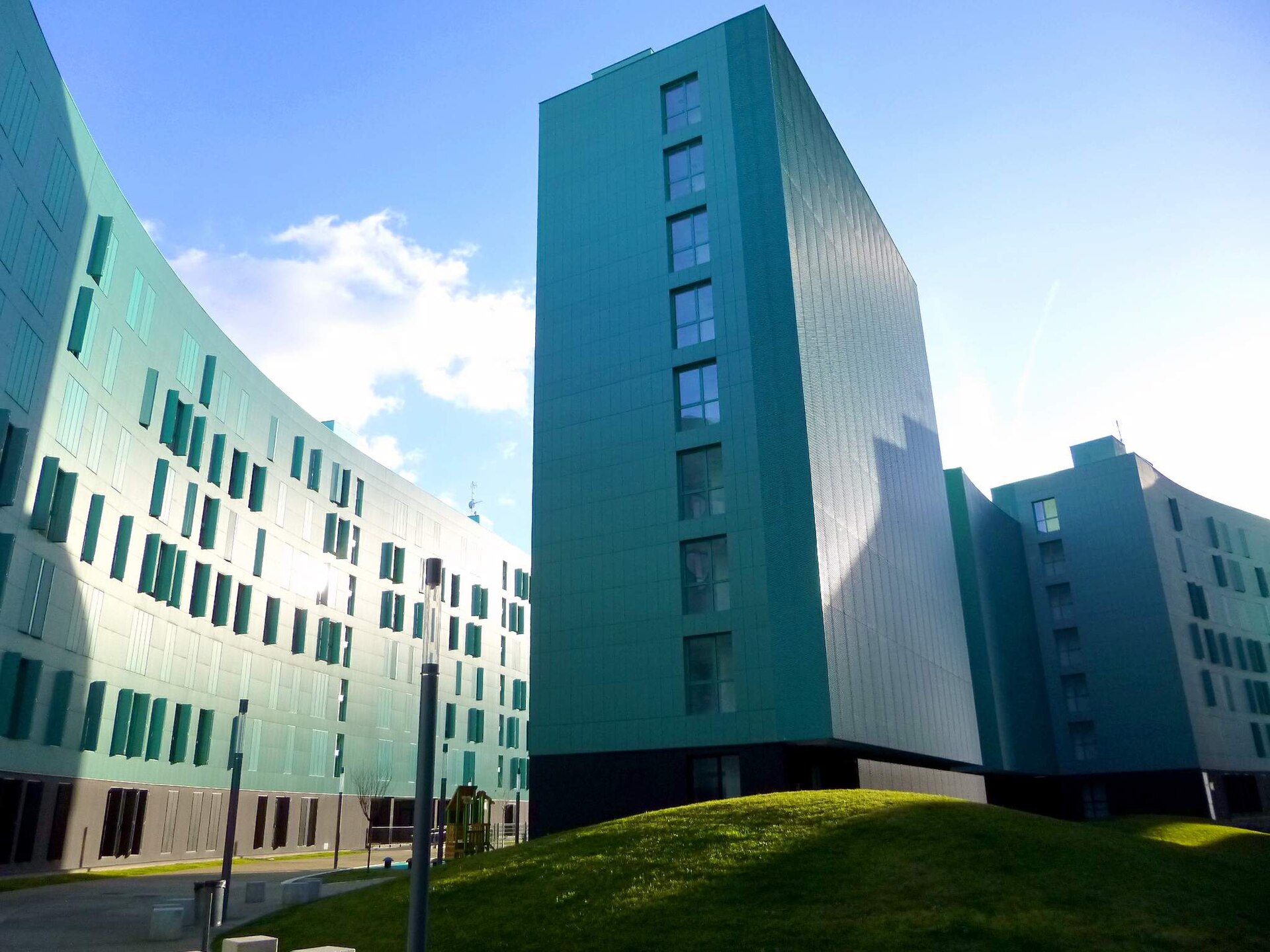 Bloques residenciales de fachada verde del complejo Pradoviejo, en Logroño, con una torre de viviendas y un edificio curvo al fondo